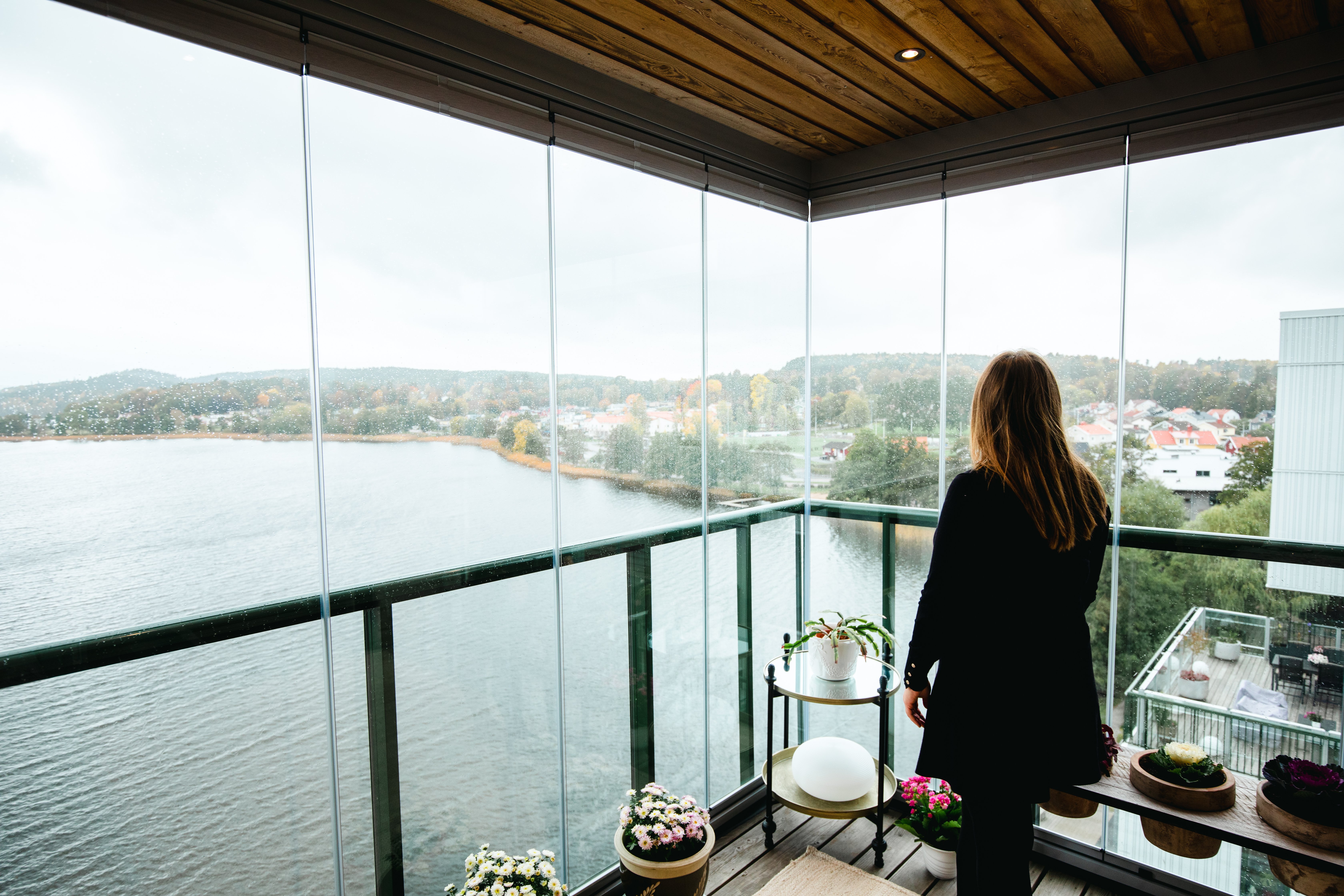 Girl looking out at scenery with lake and trees from a glazed balcony