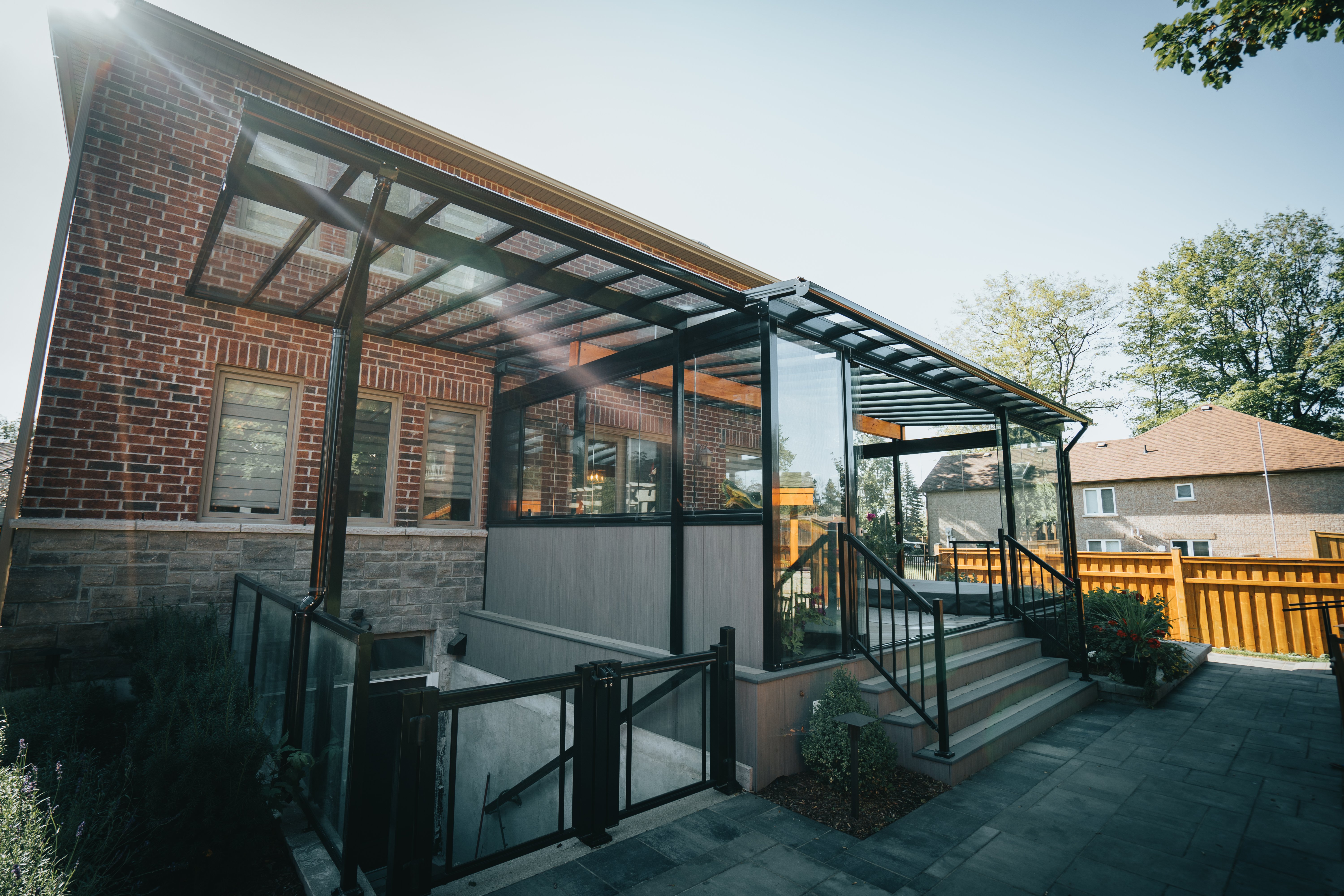 A sunroom with a black aluminum frame at the back of a brick house